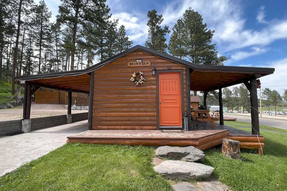 A cabin with a red door and a porch.