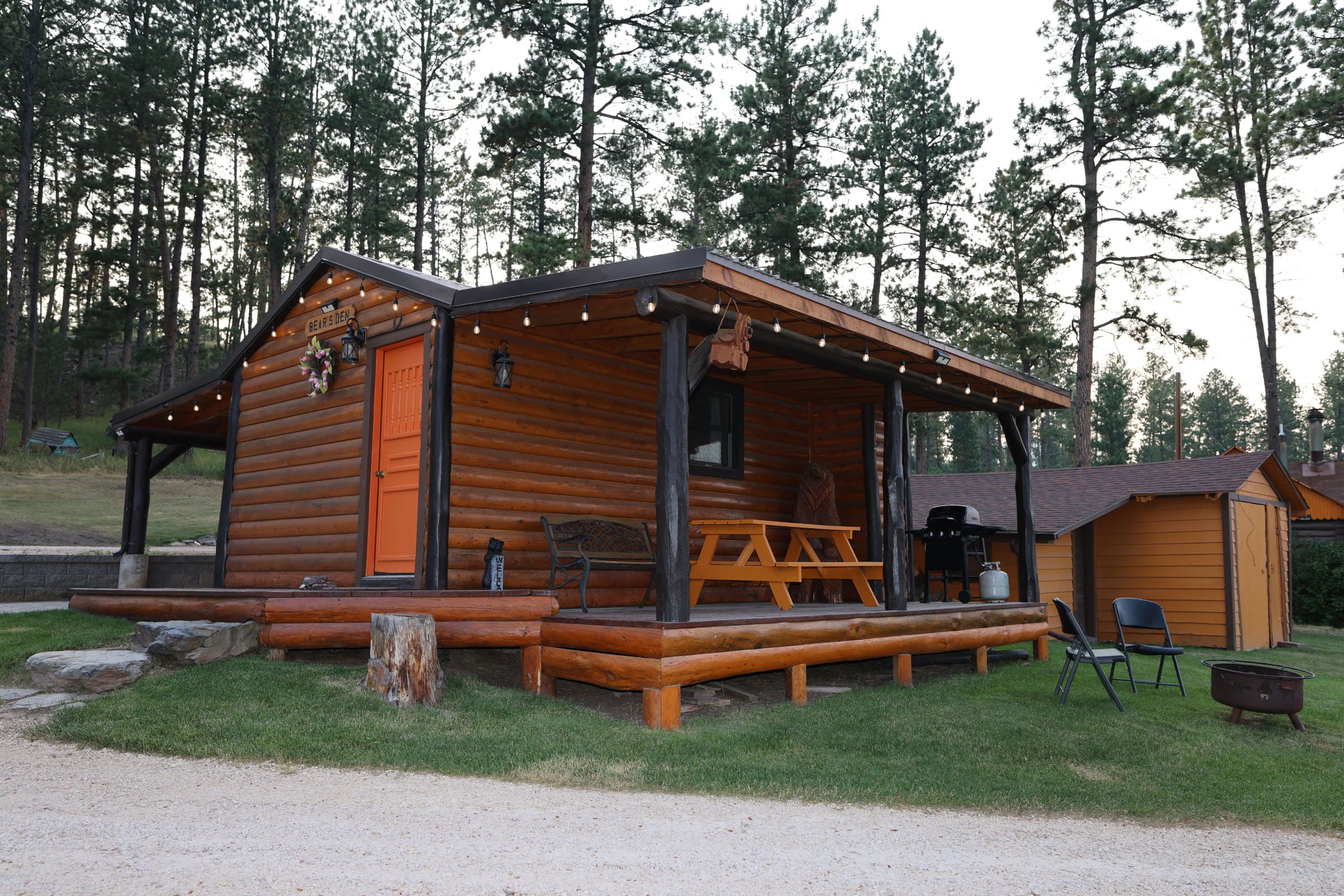 A cabin with picnic tables and lights on the side.