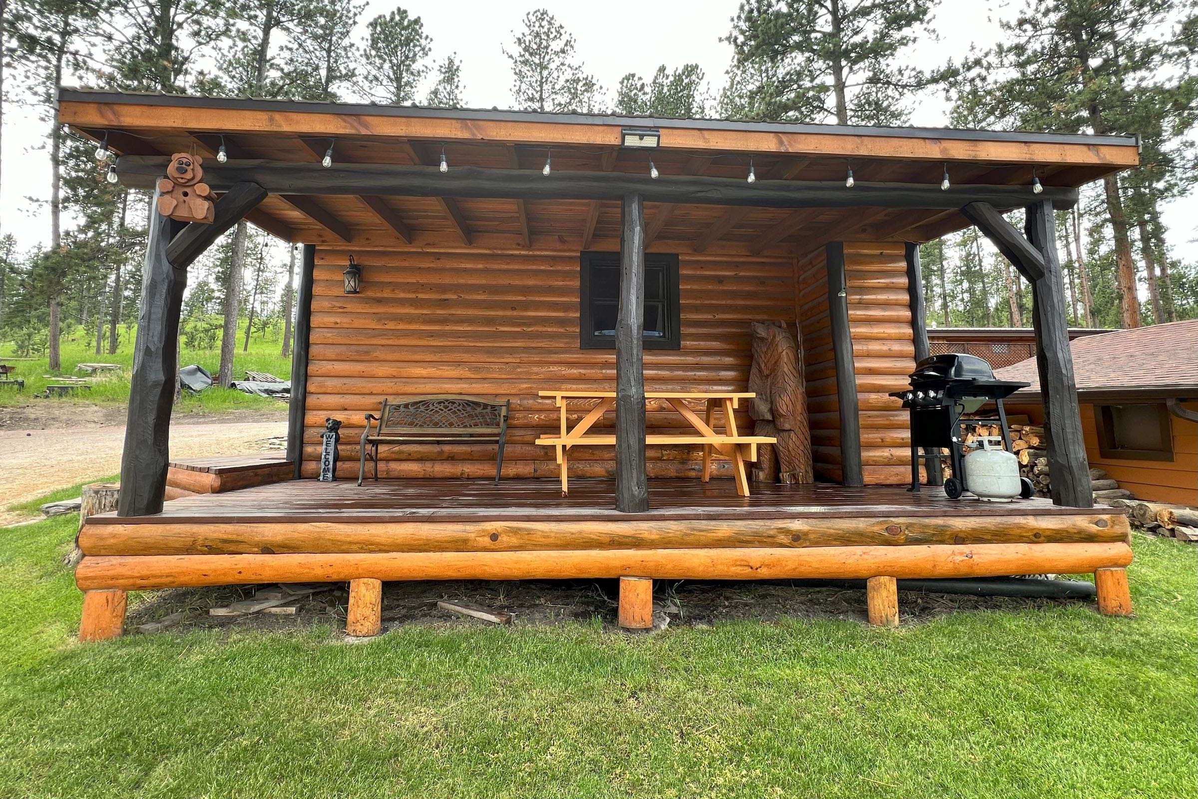 A wooden cabin with picnic tables and benches.