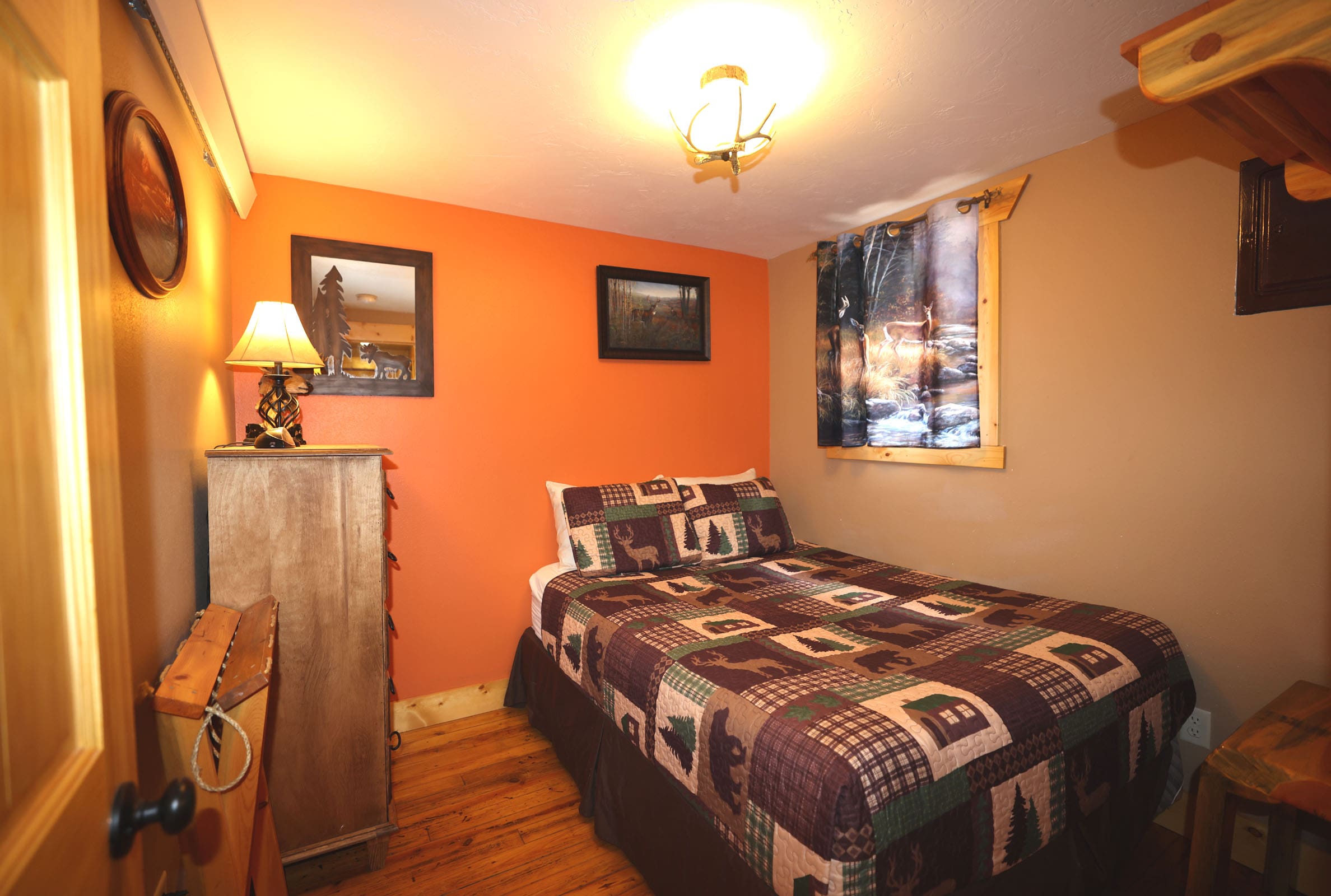 A bedroom with orange walls and wooden floors.