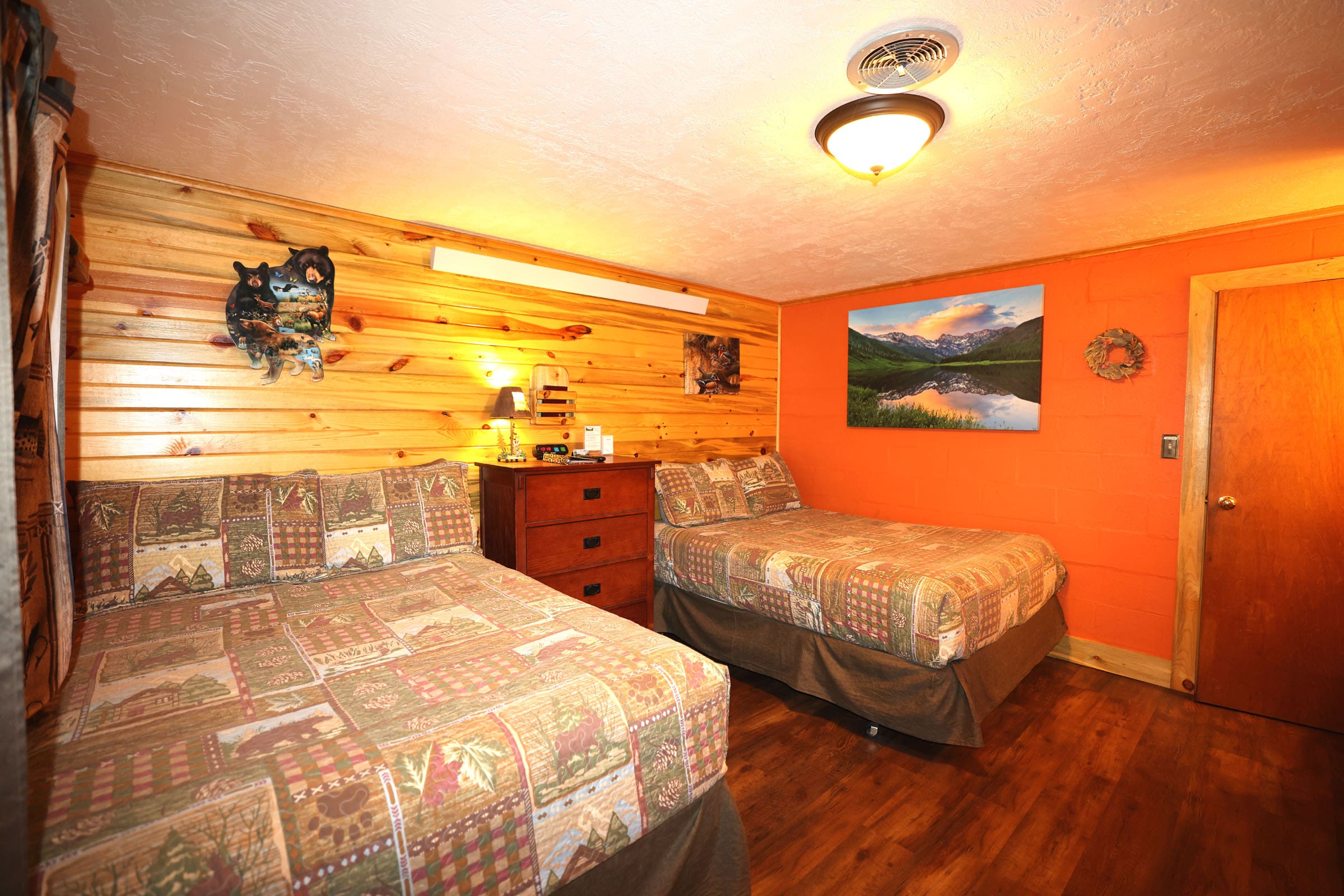 A bedroom with two beds and orange walls.