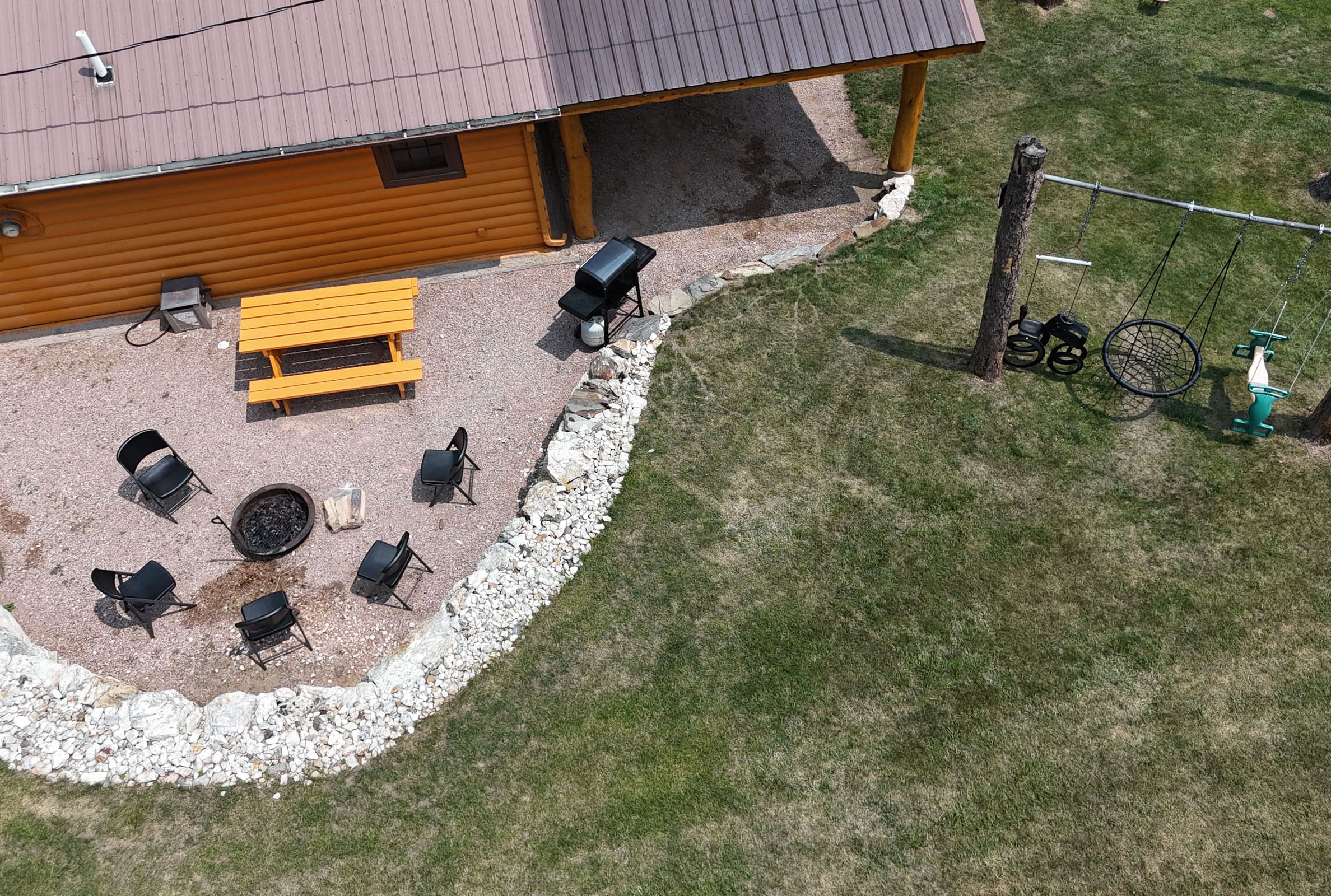 An aerial view of a cabin with a picnic table and grill.