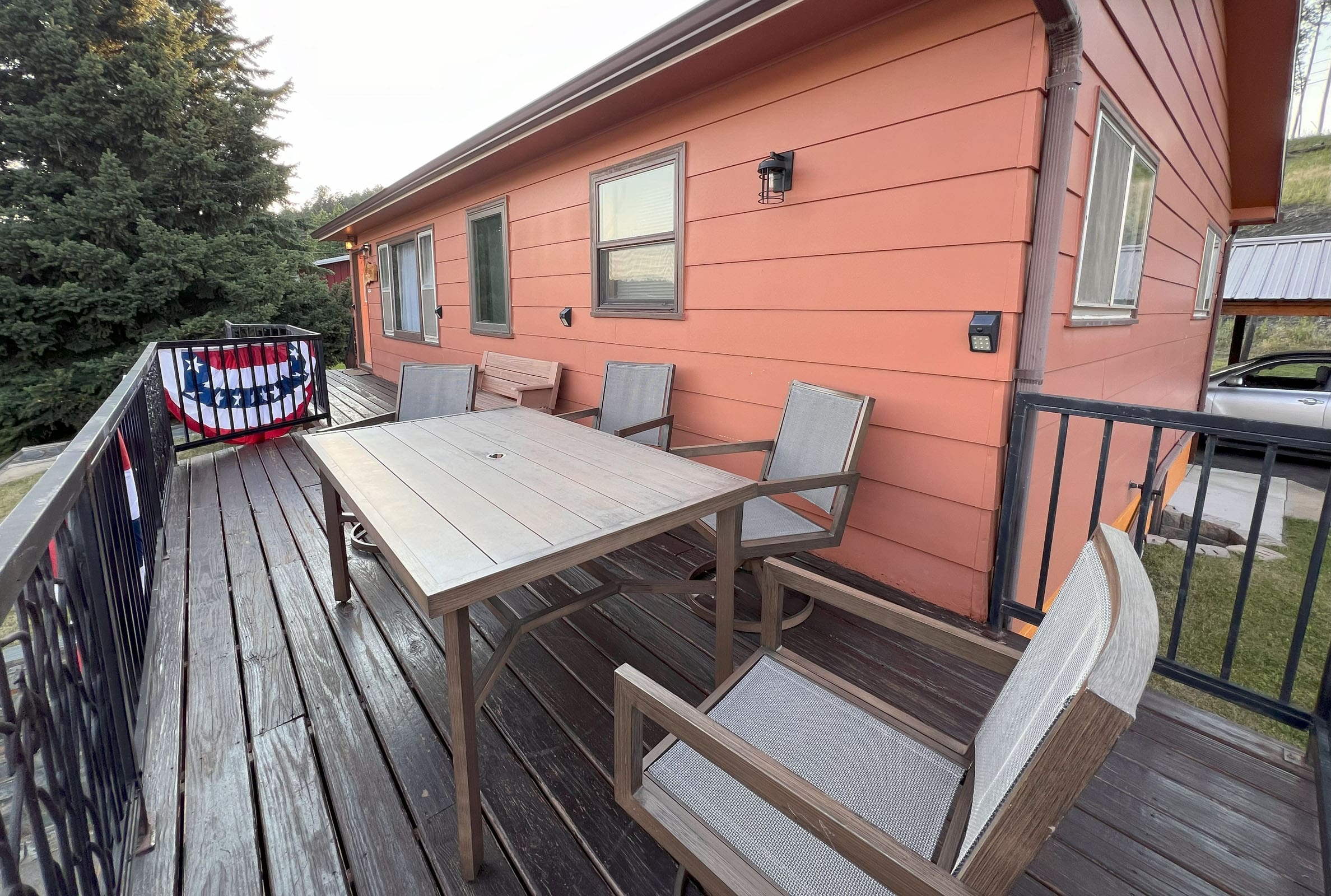 A table and chairs on the deck of an orange house.