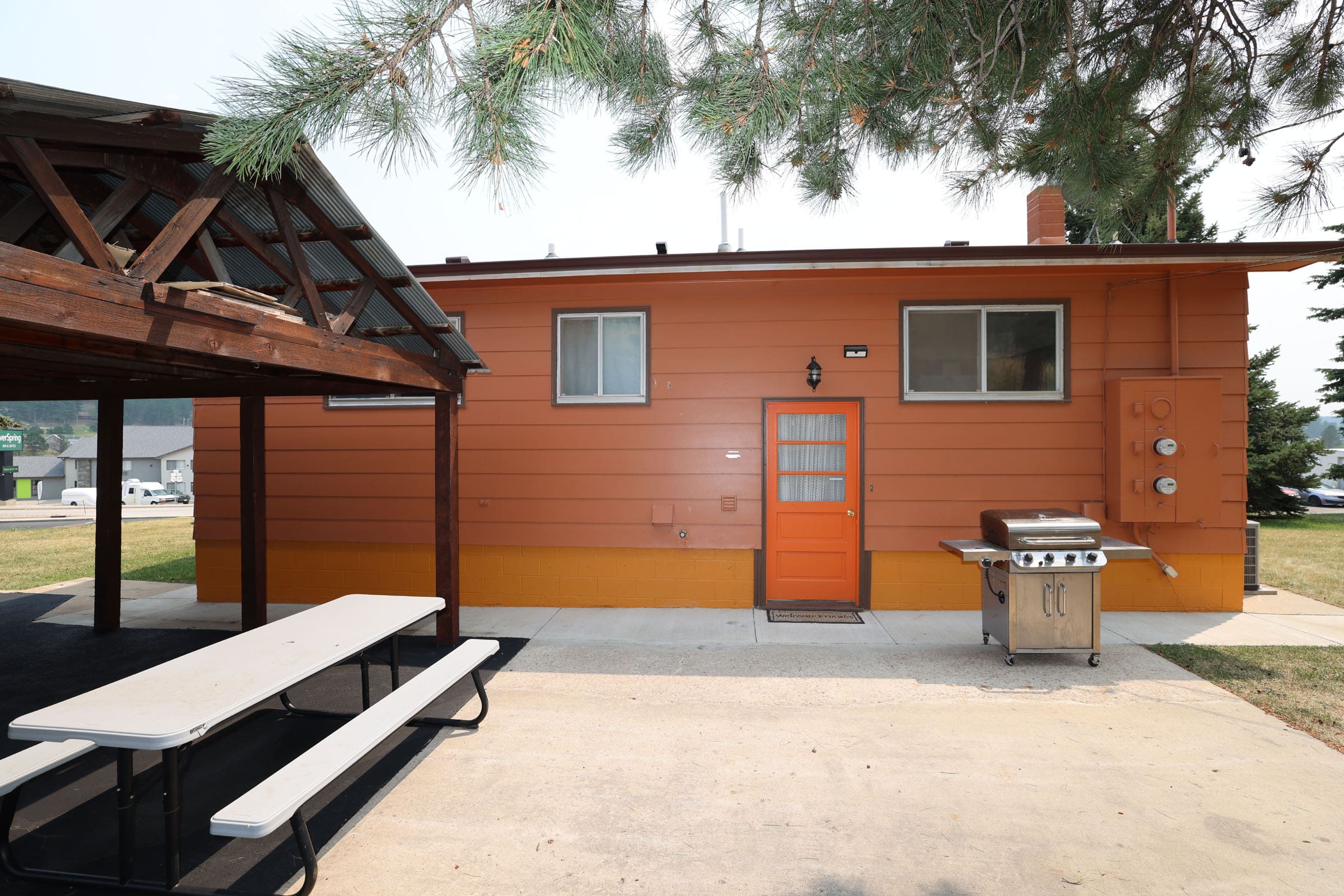 A wooden house with an orange door and white trim.