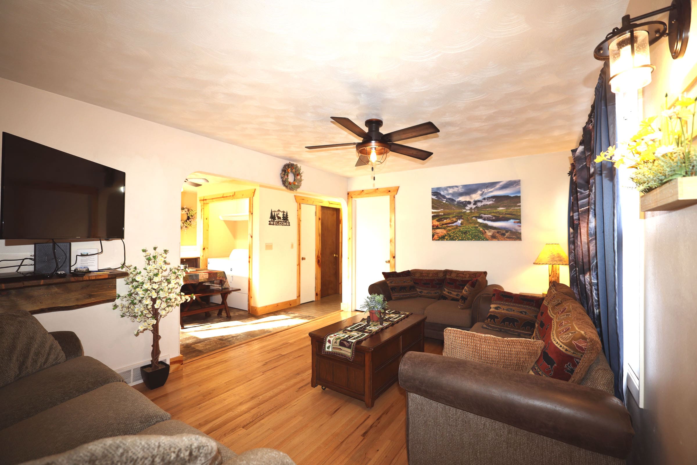 A living room with couches, a table and a ceiling fan.