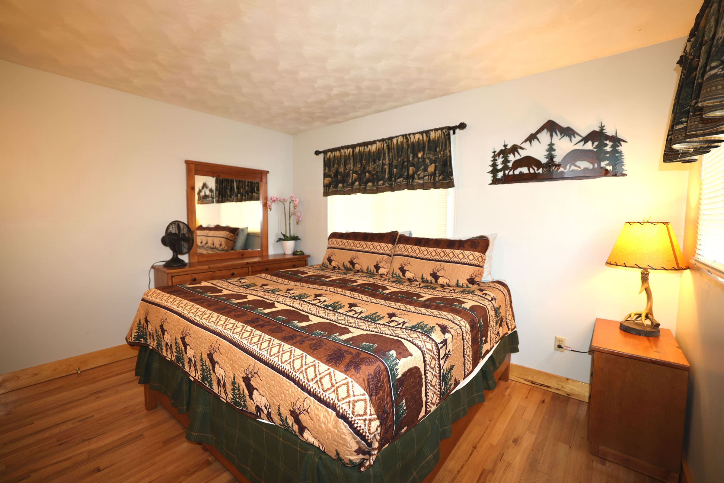 A bedroom with a bed, dresser and mirror.