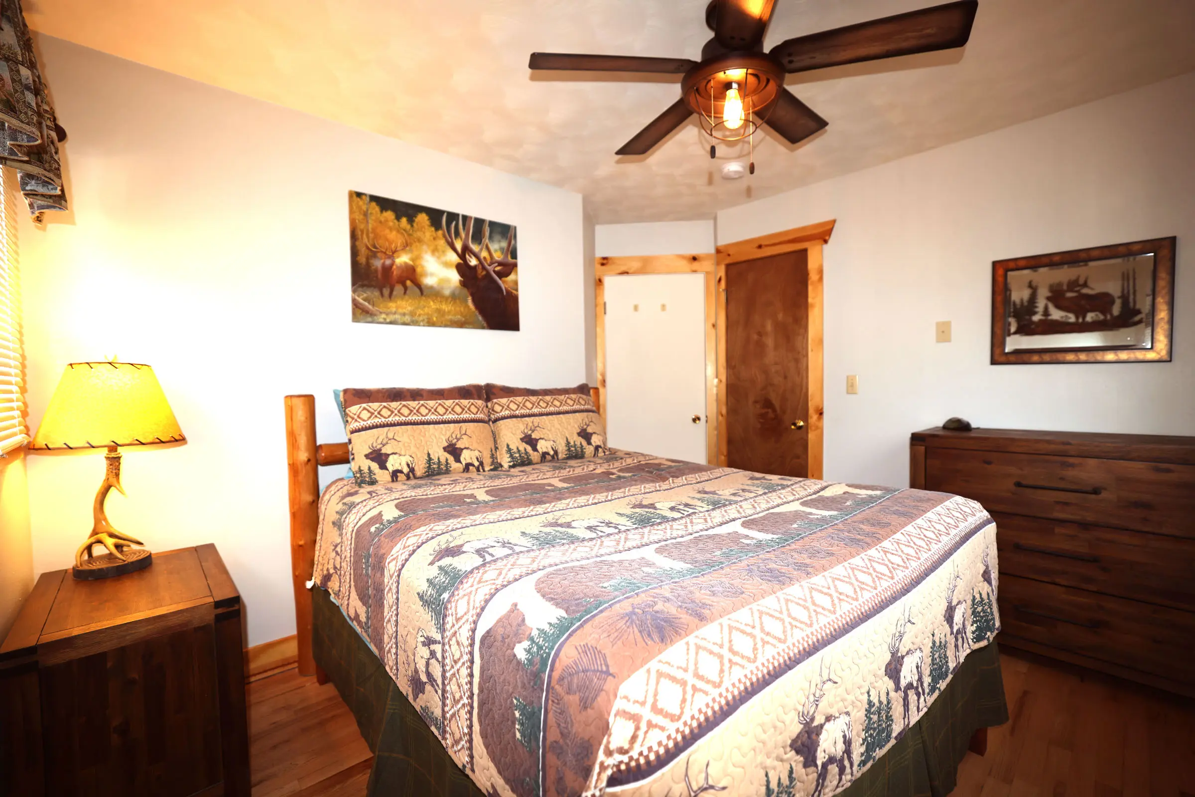 A bedroom with a bed, dresser and ceiling fan.