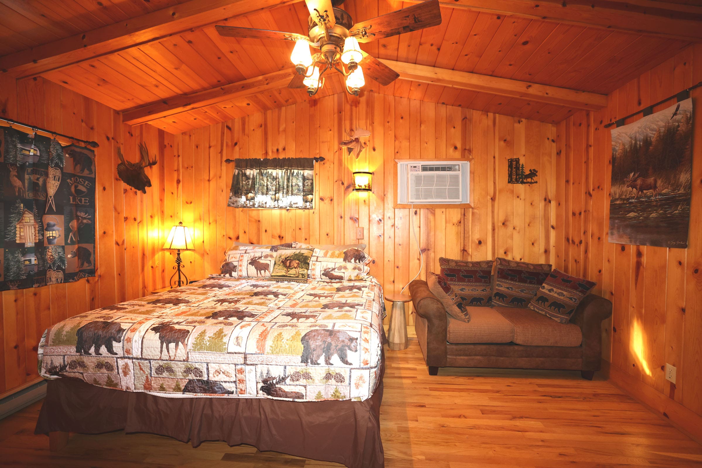 A bedroom with a bed, couch and ceiling fan.