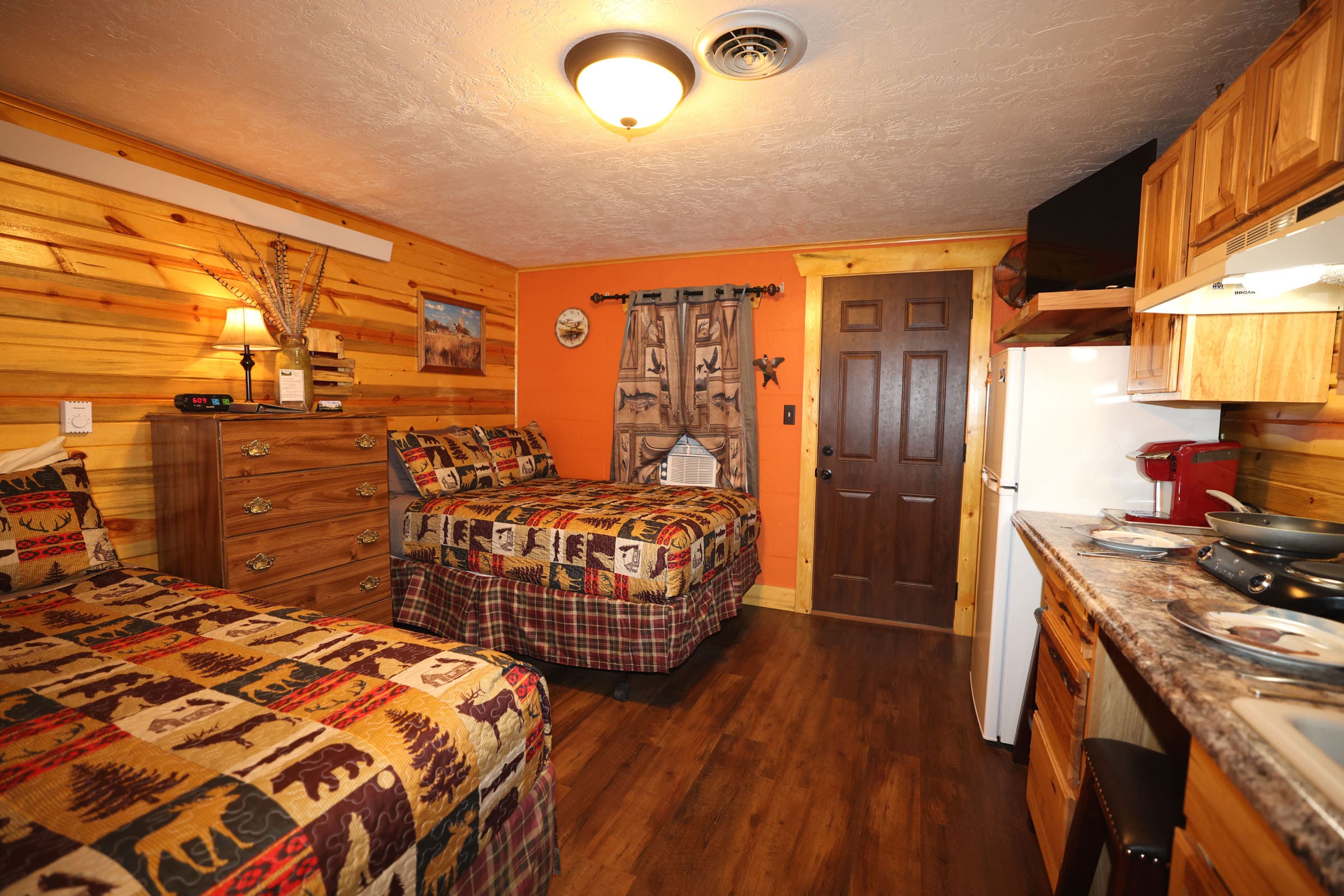 A room with two beds and a door to the kitchen.