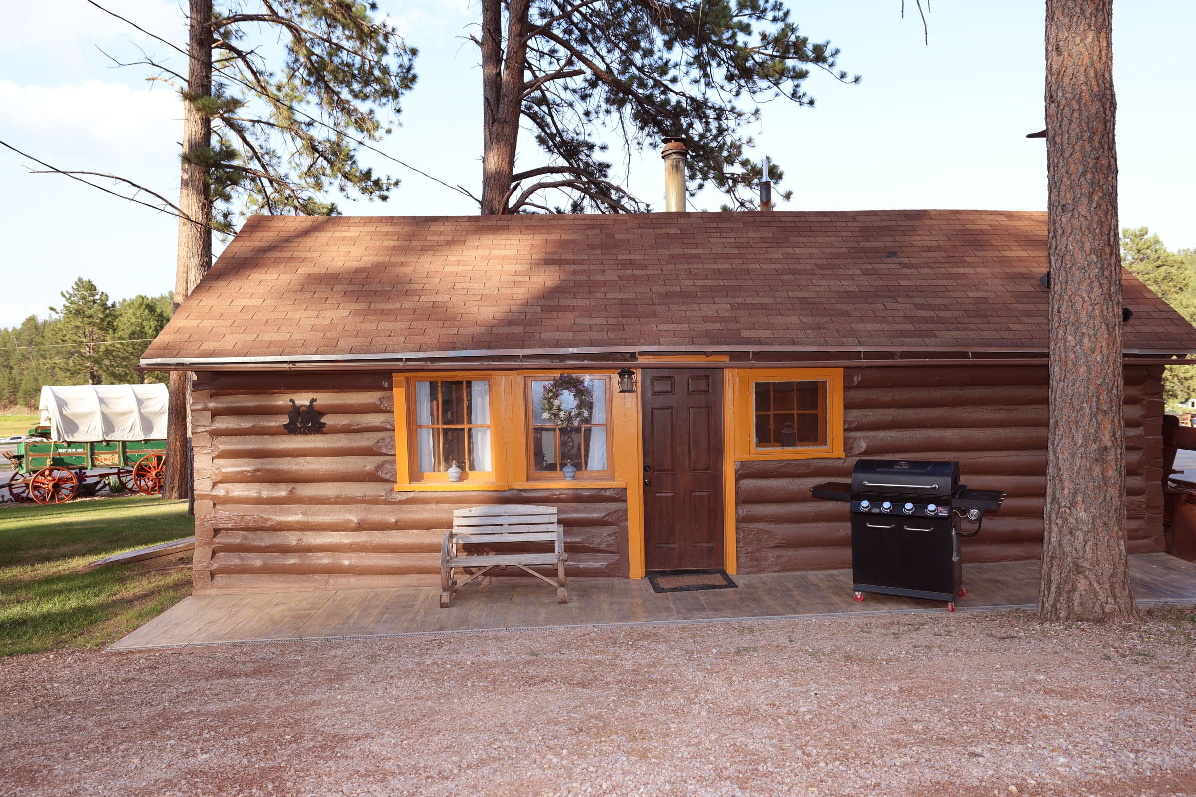 A cabin with a grill and bench outside of it