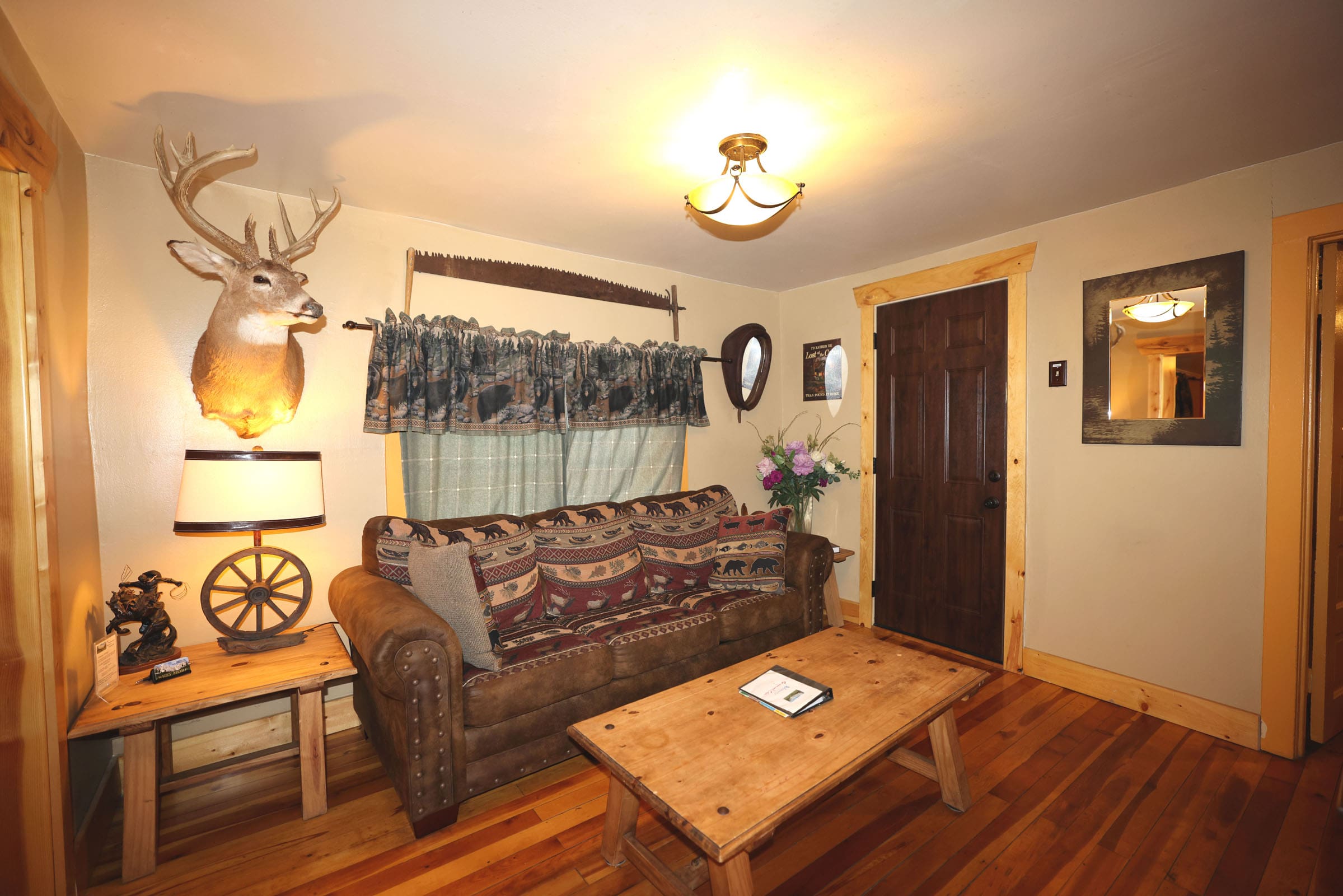 A living room with a couch, table and deer head on the wall.