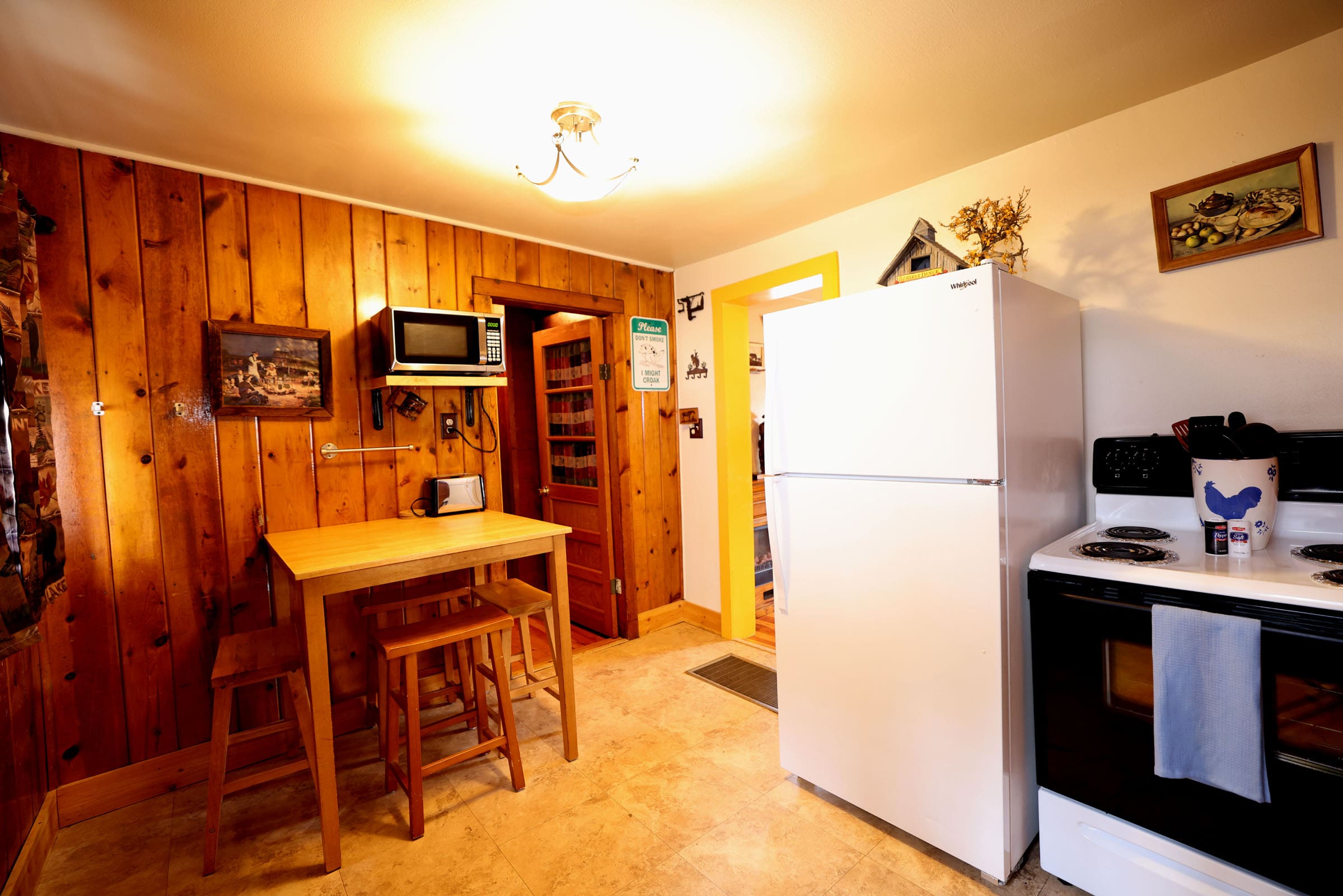 A kitchen with a refrigerator, microwave and table.