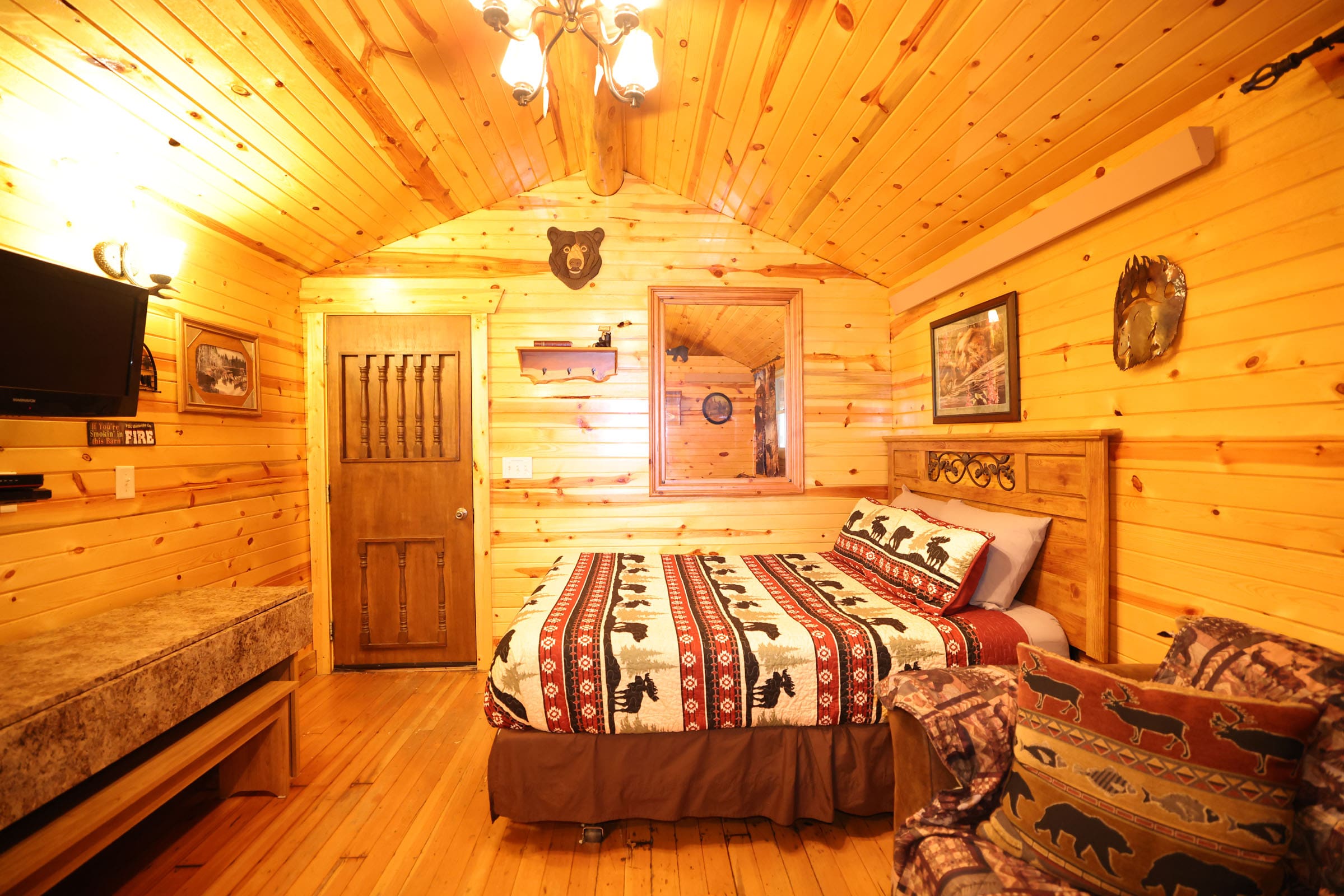 A bedroom with wood paneled walls and wooden floors.