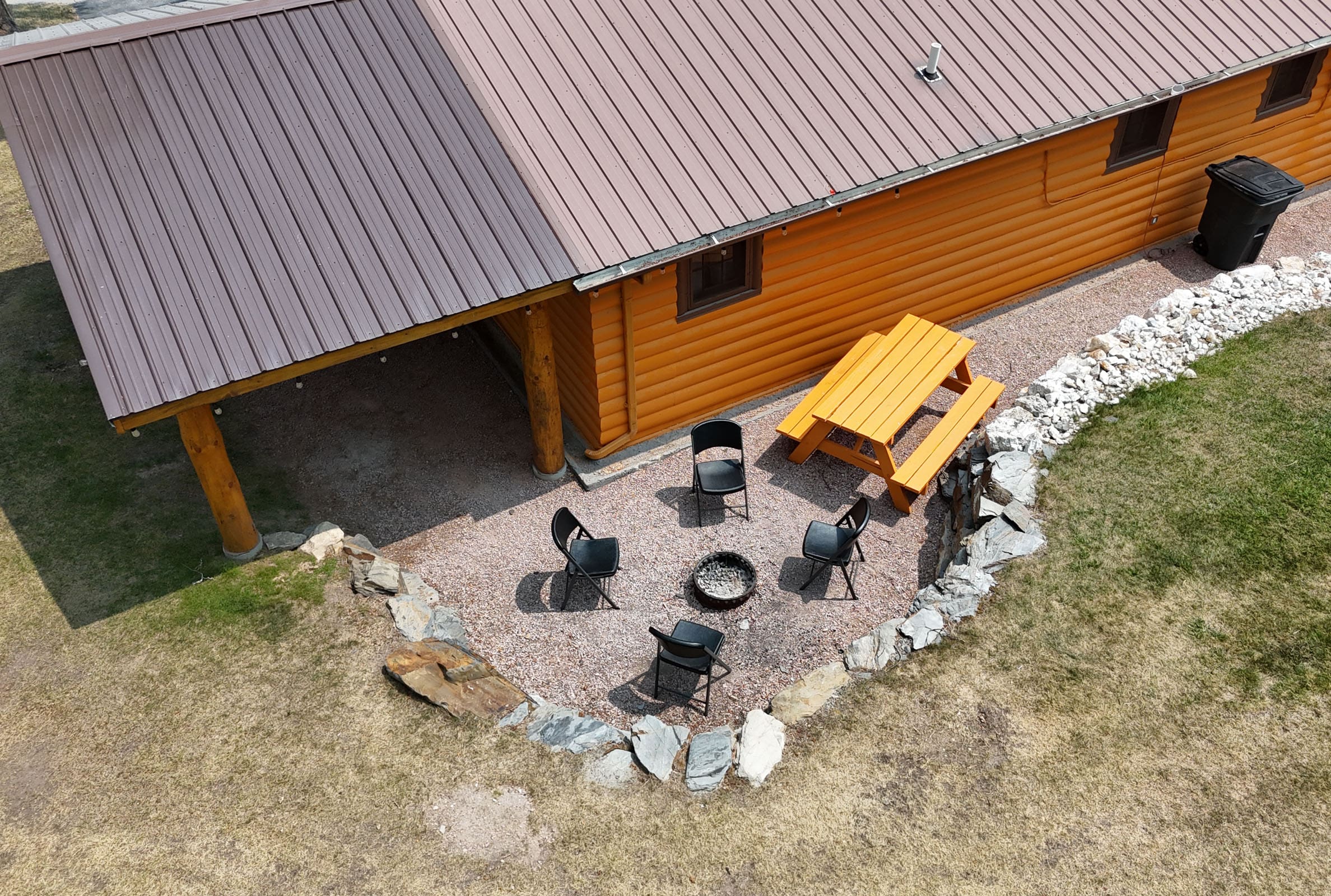 A patio with chairs, fire pit and table.