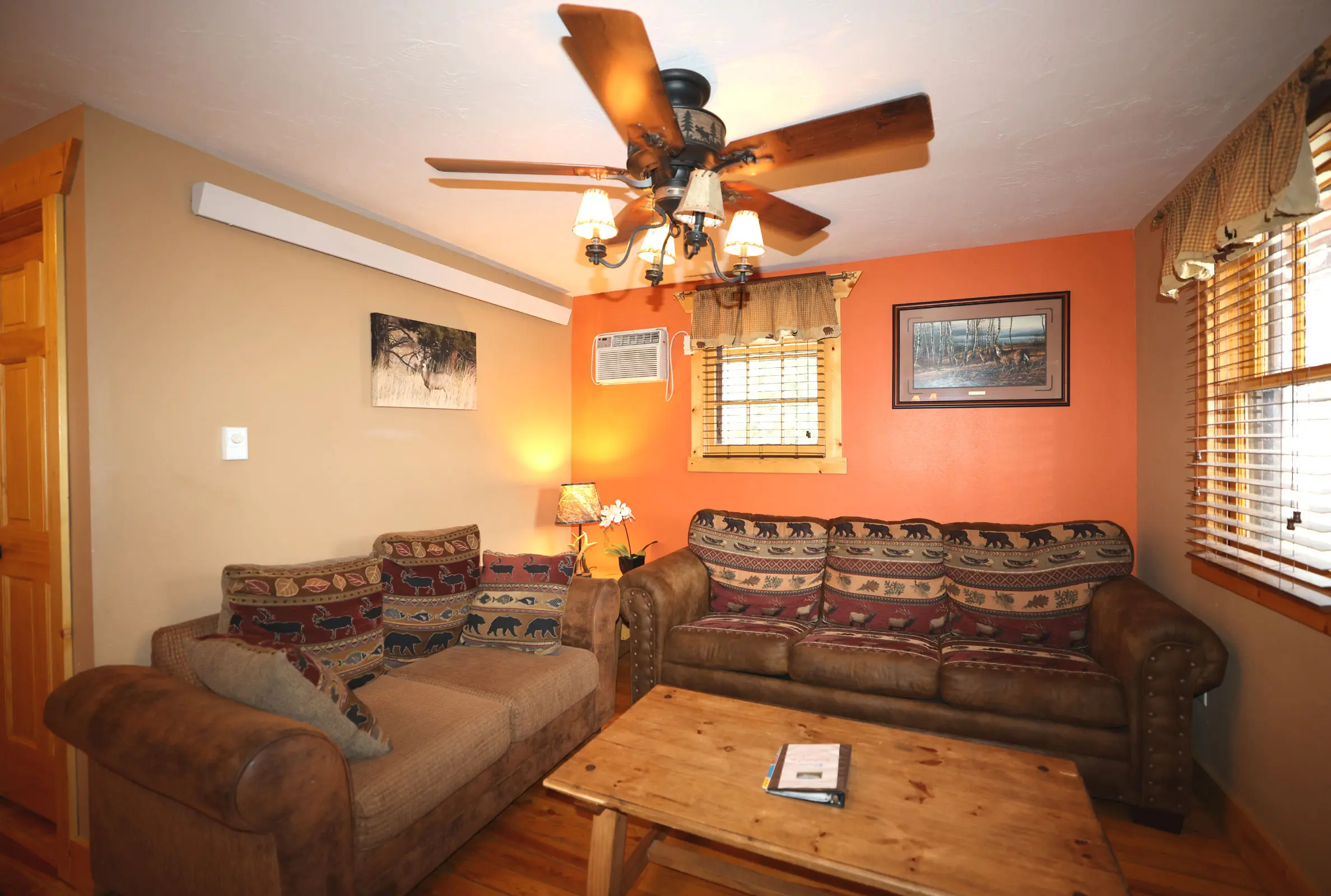 A living room with couches and a ceiling fan.