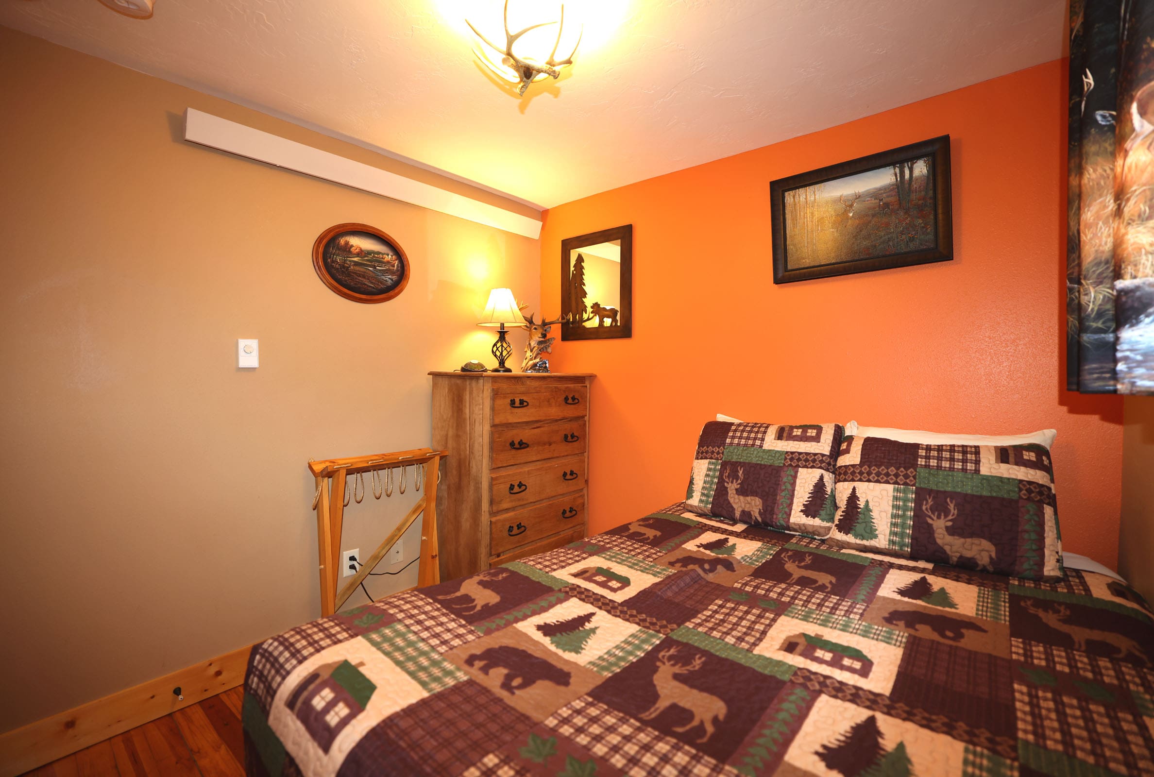 A bedroom with an orange wall and brown bed