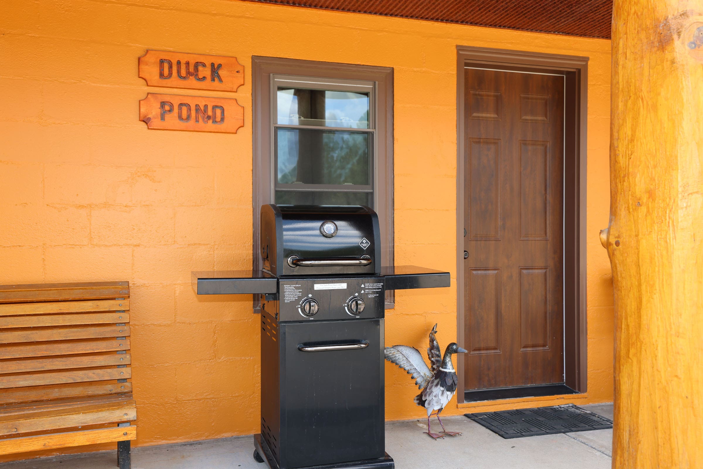 A black grill sitting outside of a yellow house.