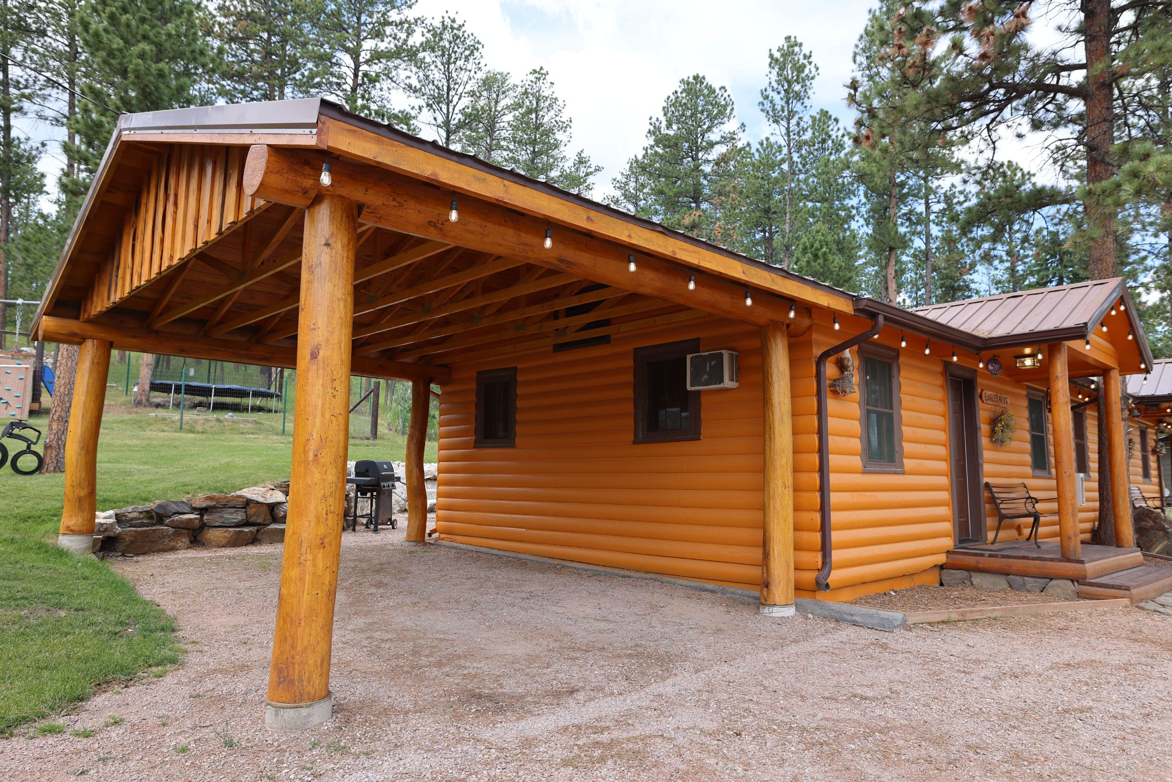 A wooden cabin with a metal roof and a large open porch.