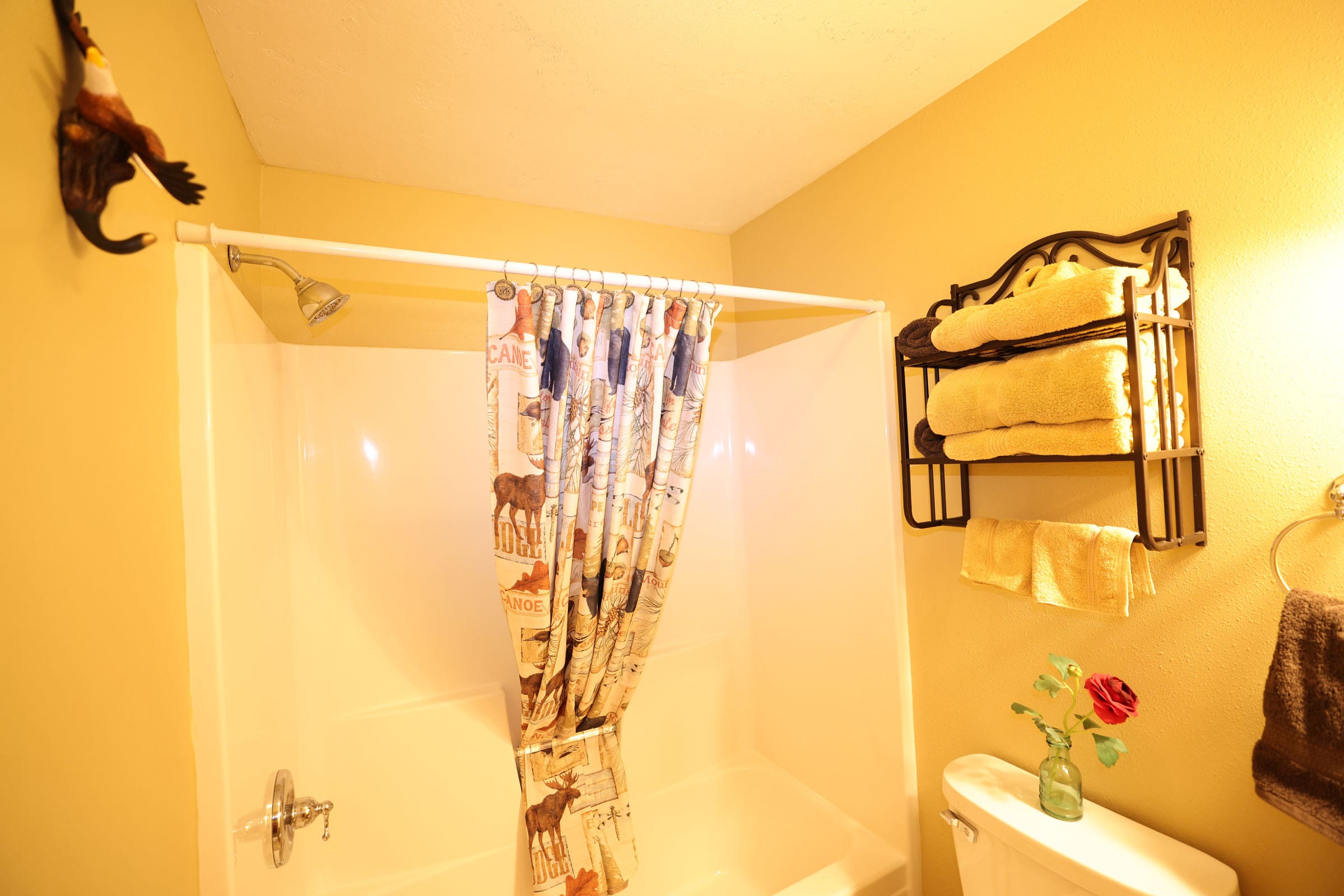 A bathroom with a shower curtain and towels hanging on the wall.