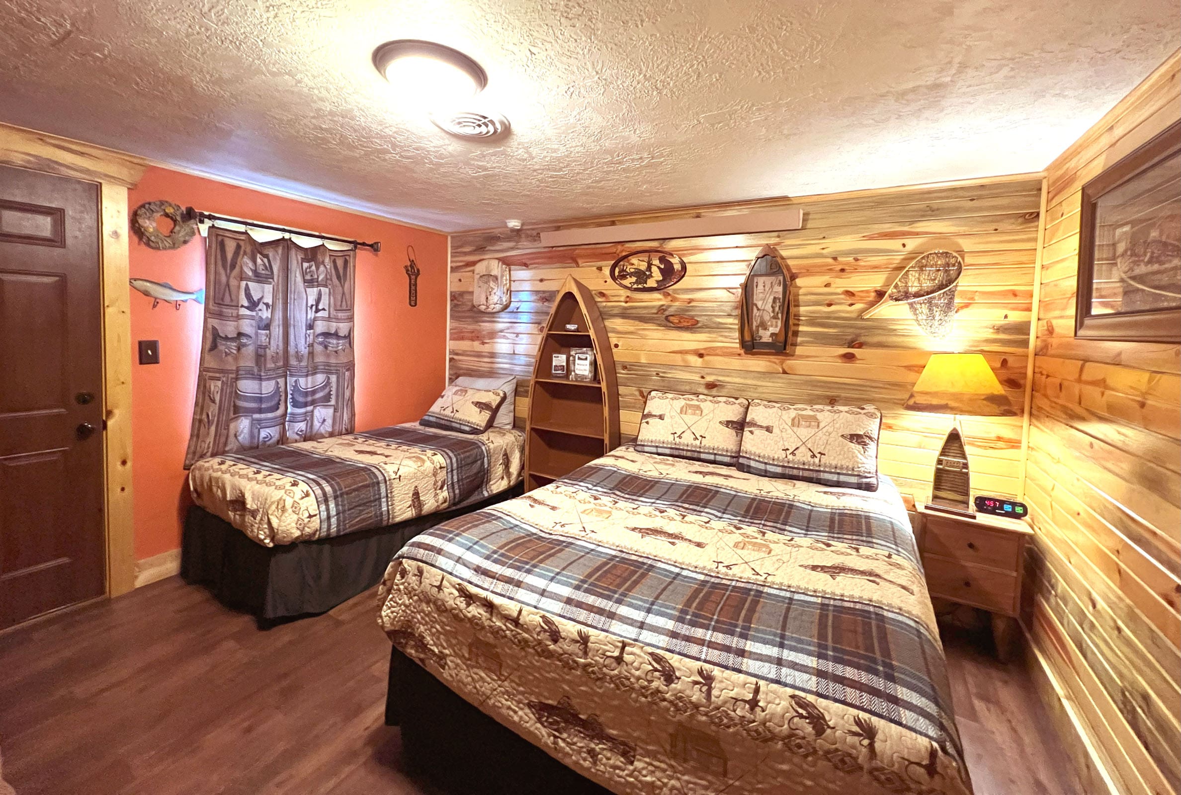 A room with two beds and a wall of wood.