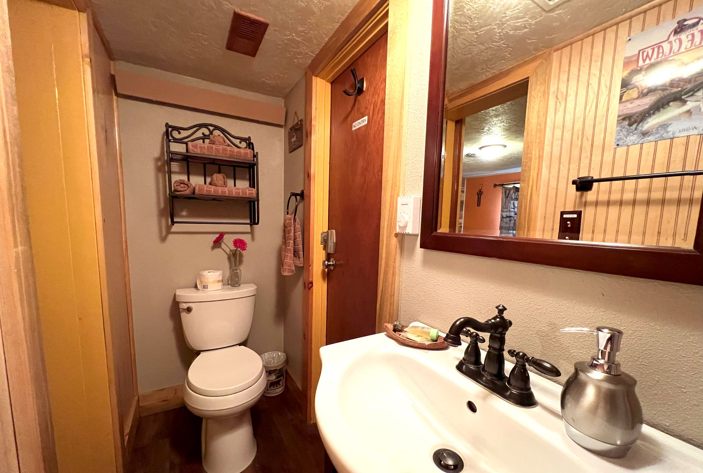 A bathroom with a toilet, sink and mirror.