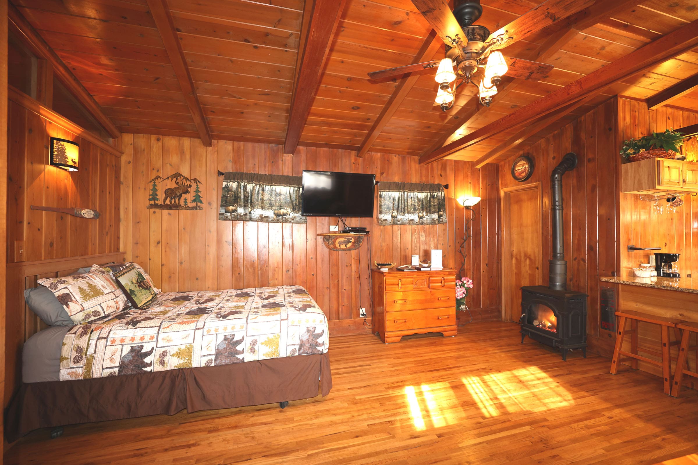 A bedroom with wood paneled walls and floors.