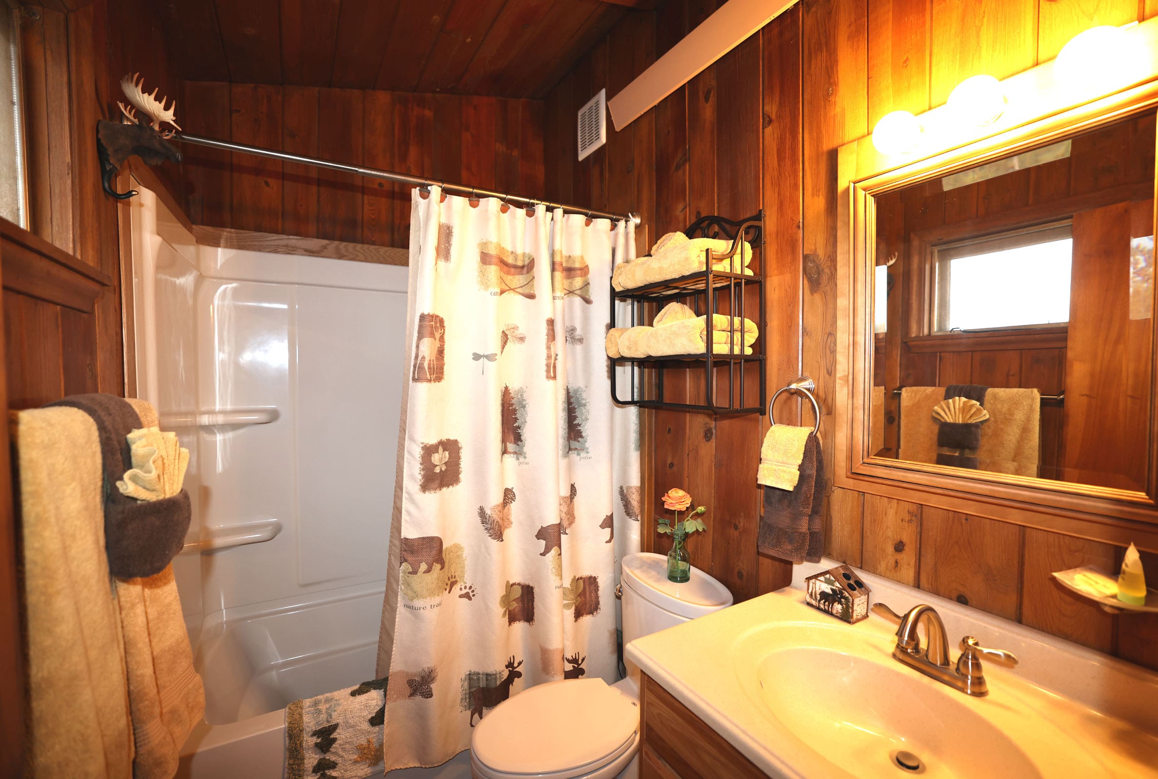 A bathroom with wood paneled walls and white fixtures.