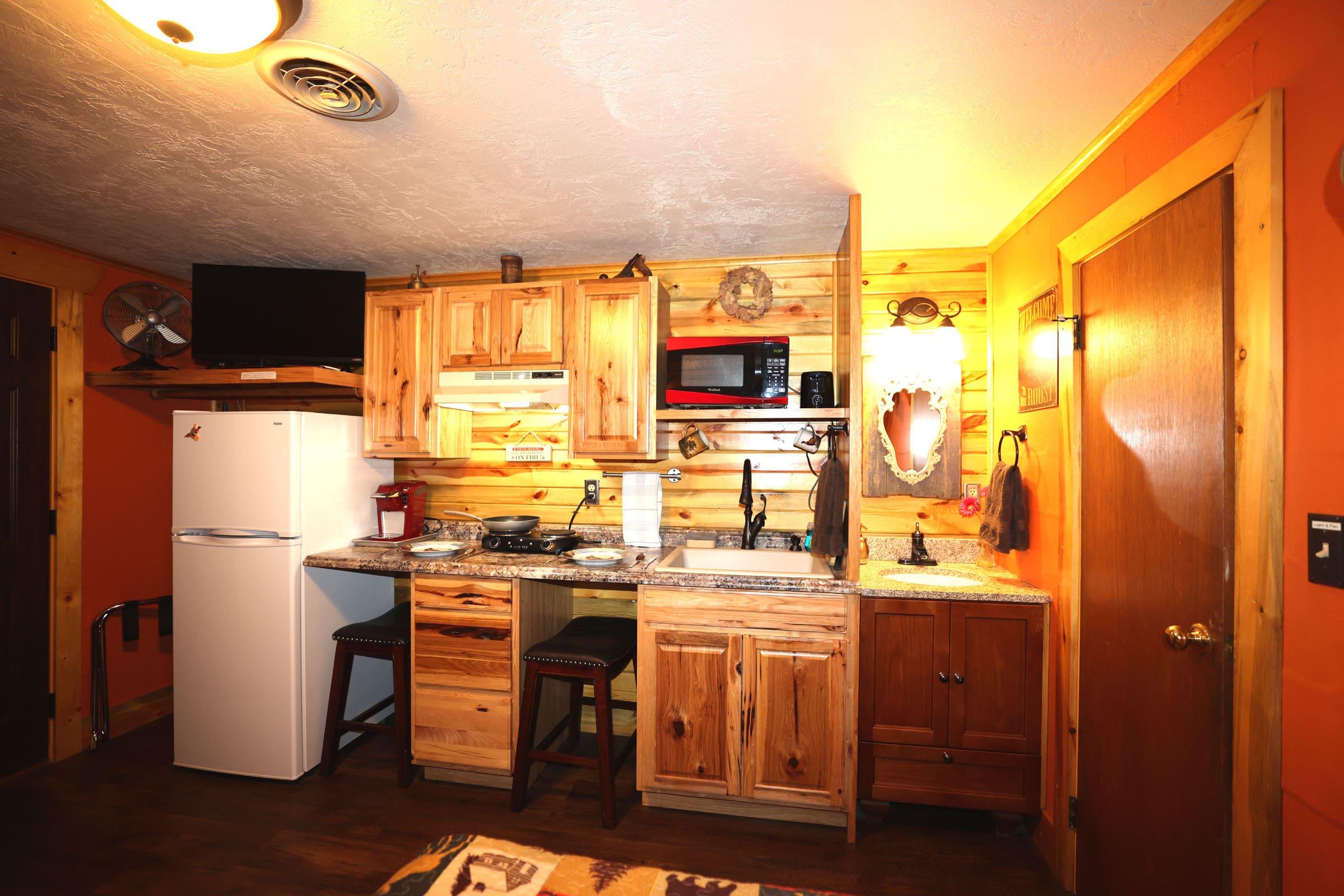 A kitchen with wooden cabinets and wood floors.