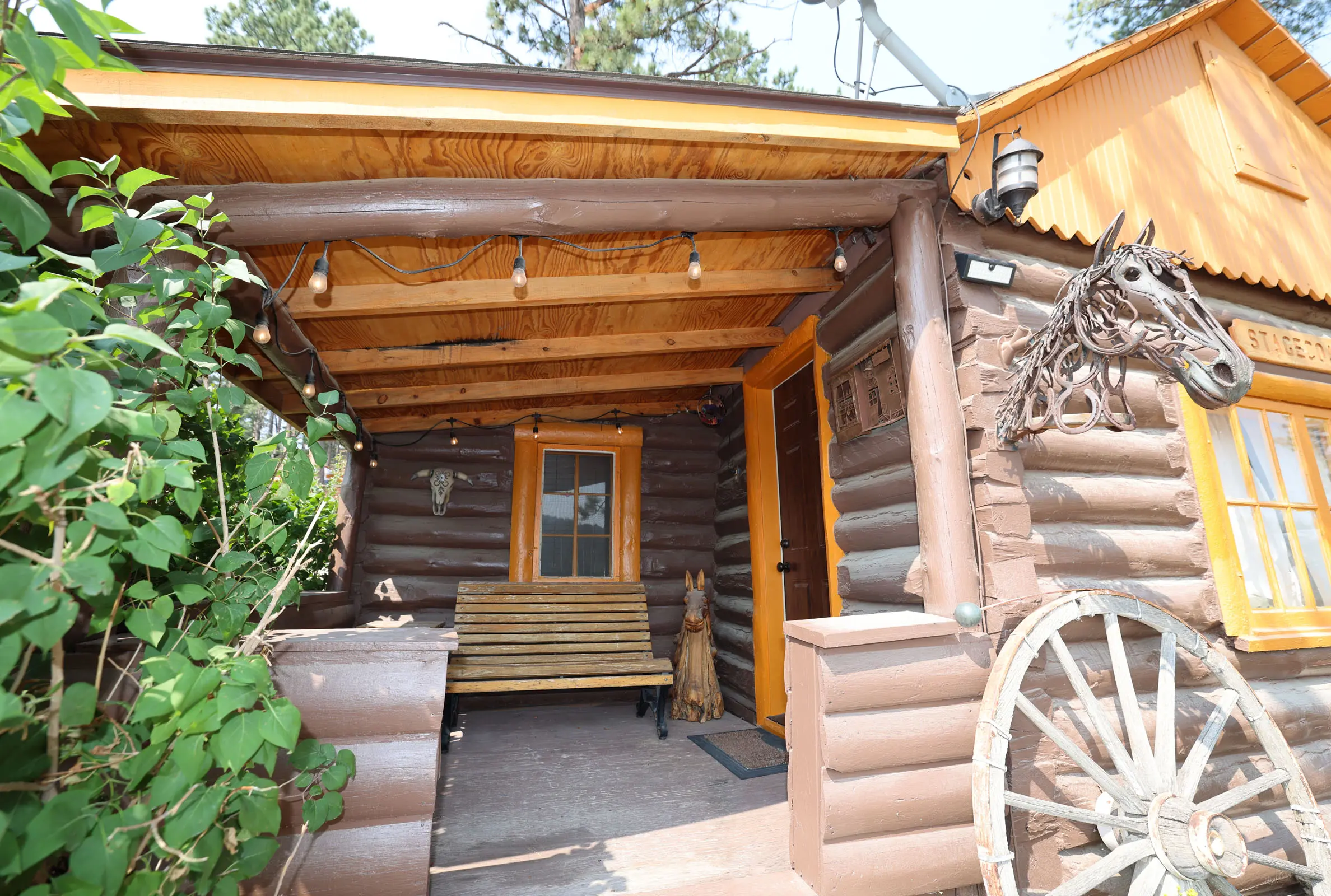 A cabin with a bench and wagon wheel.