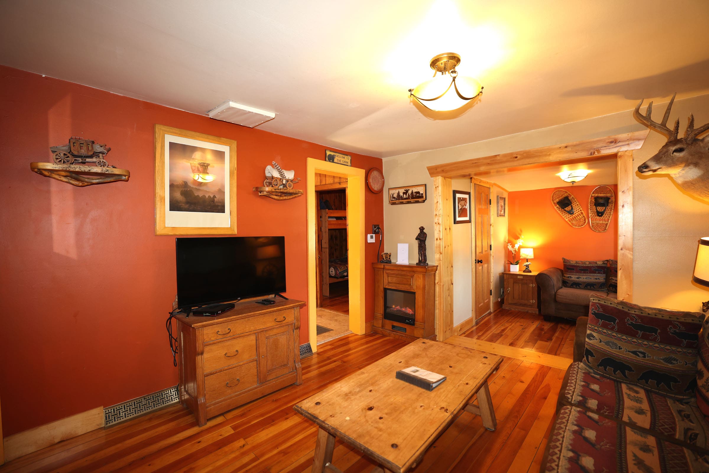 A living room with wood floors and orange walls.