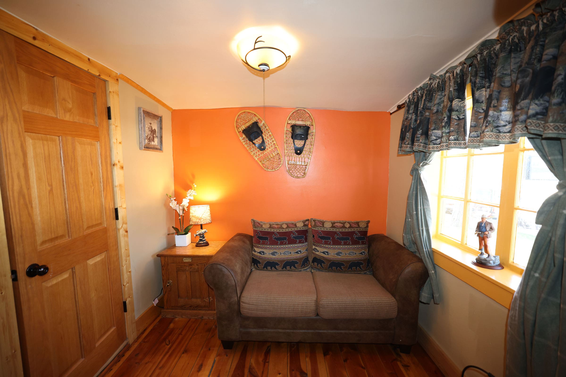 A living room with orange walls and brown furniture.