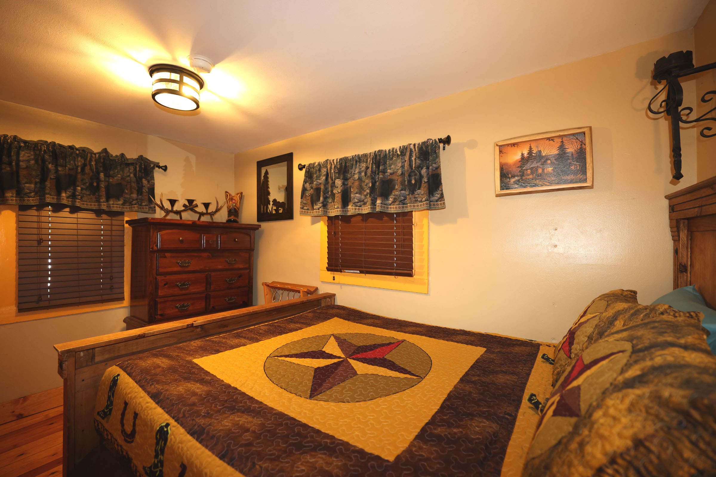 A bedroom with a bed, dresser and pictures on the wall.